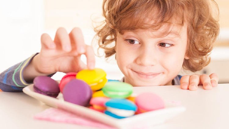Little boy licking his lips while taking candy from the candy jar.