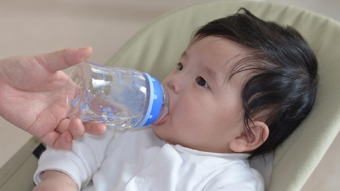Mother give baby water from baby bottle, baby likes it