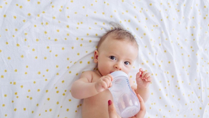 Mother give baby water from baby bottle, baby likes it