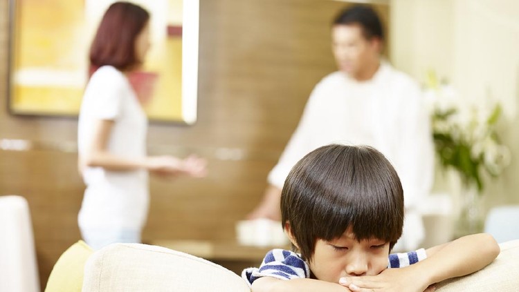 parenting asian child appears sad and unhappy while parents quarreling in the background.