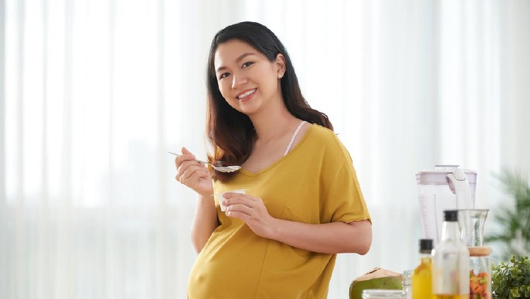 Young beautiful pregnant woman preparing healthy meal with fruites and vegetables