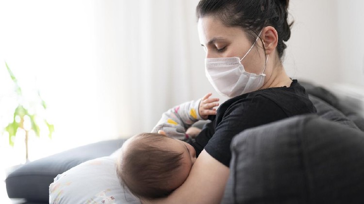 Mother with mask breastfeeding her little baby