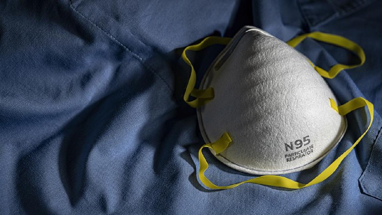 N95 PPE protective mask resting on blue medical scrubs with copy space