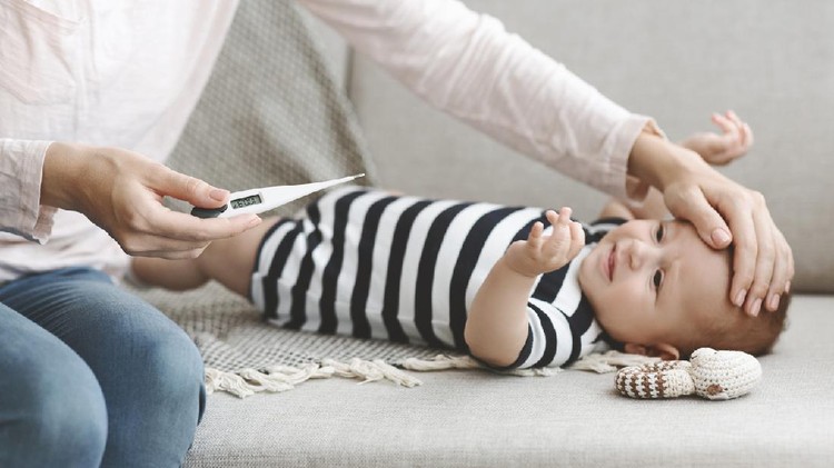 Newborn cold. Mother holding thermometer and touching forehead of her sick baby, measuring temperature, panorama