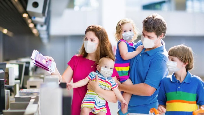 Family in airport in face mask. Virus outbreak. Coronavirus and flu pandemic. Safe travel with young child and baby. Mother, father and kids boarding airplane in surgical masks.