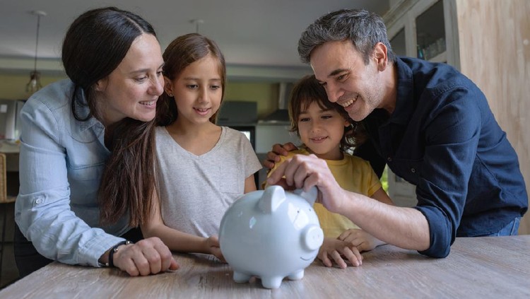 Loving latin american parents teaching their kids to save money in a piggy bank all smiling