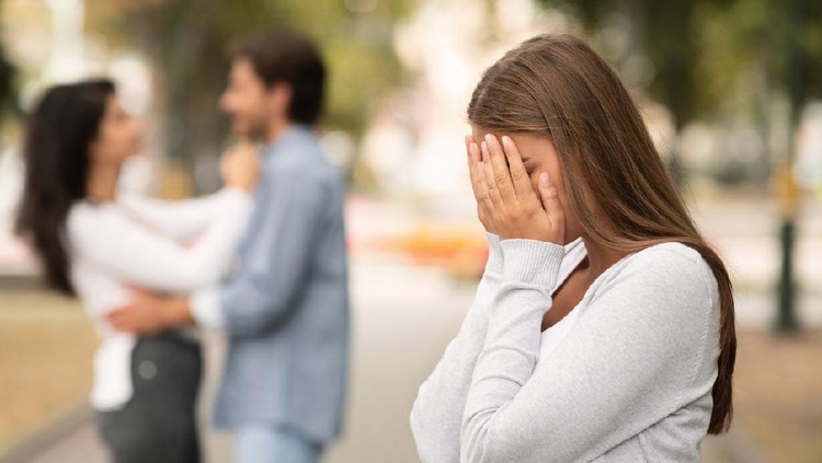 Upset woman crying, seeing her boyfriend with other girl in park