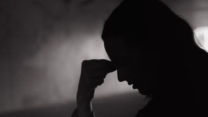 Young woman feeling sad in a dark setting.