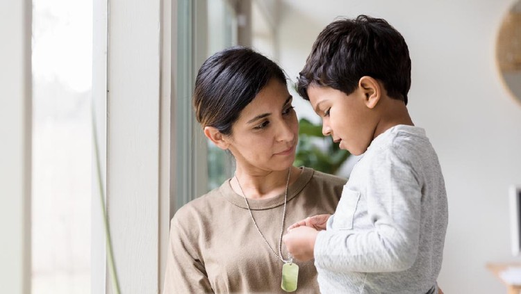 As she stands by the window of their home carrying her young son, the mid adult single mother listens quietly as the boy talks about her deployment.