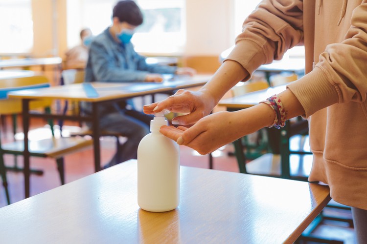 School students  using hand sanitizer after entering a classroom.