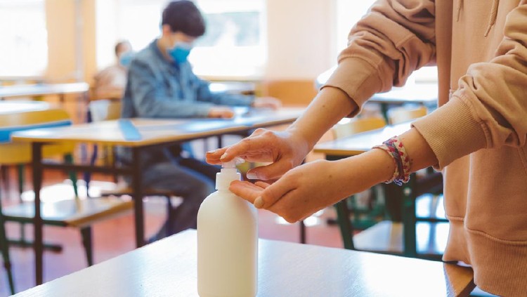 School students  using hand sanitizer after entering a classroom.