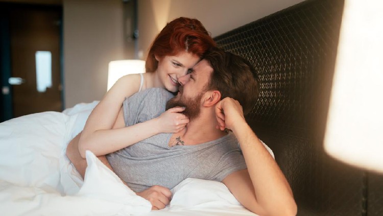 Couple in love lying on bed and touching each other tenderly