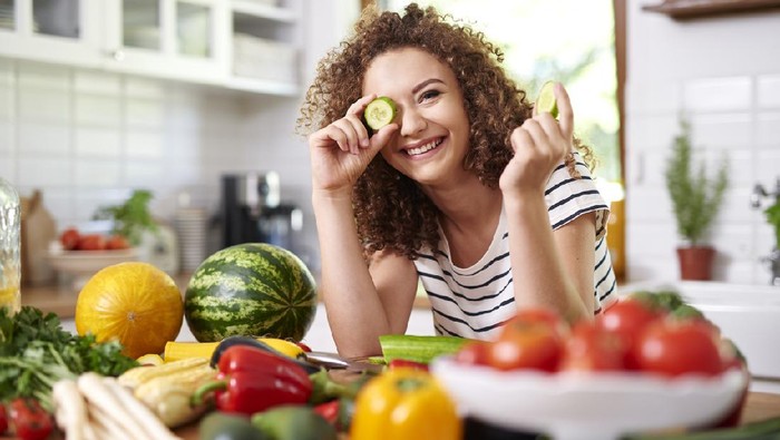Woman holding a slice of cucumber