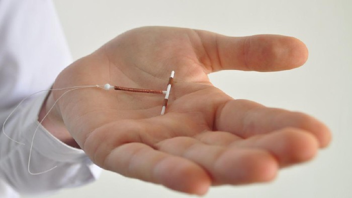 Holding an IUD birth control copper coil device in hand, used for contraception - side view