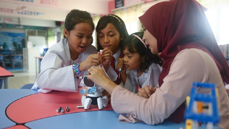 Asian elementary schoolgirls and female teacher building robot in science class