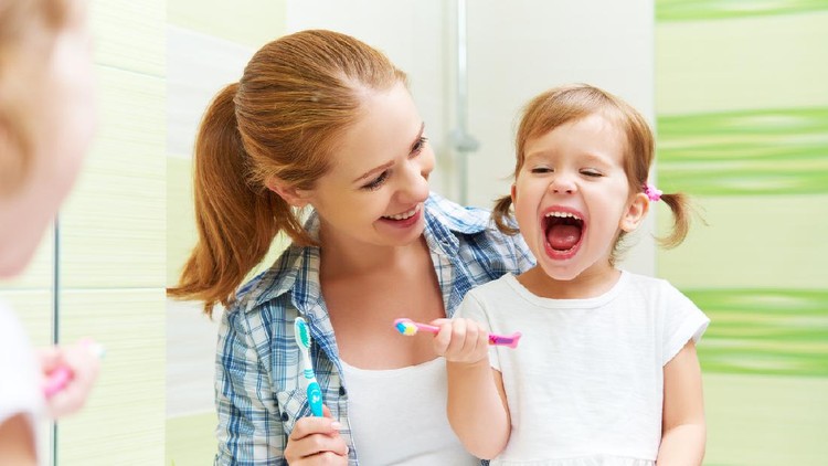 Child brushing teeth. Kids tooth brush and paste. Little baby boy in blue bath robe or towel brushing his teeth in white bathroom with window on sunny morning. Dental hygiene and heath for children.