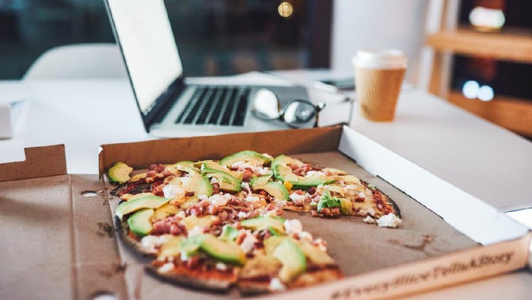Shot of a pizza on desk in a modern office late at night