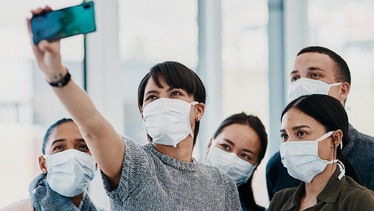 Shot of a group of young people wearing masks and taking selfies at the airport