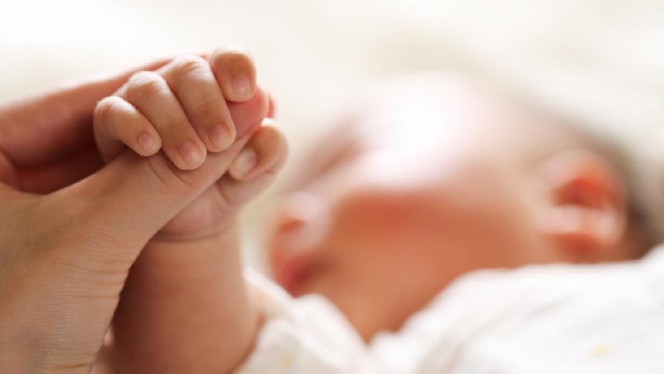 Sleeping baby clenches his parent's fingers; Soft focus and blurry