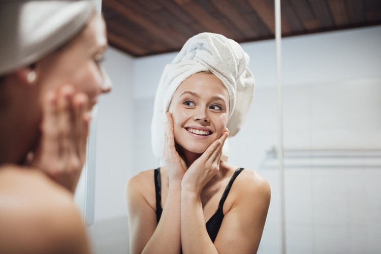 Membersihkan wajah Girl with towel is lookin in a mirror