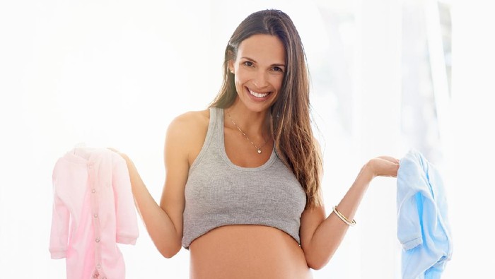 Shot of a pregnant woman holding a pink and blue onesie