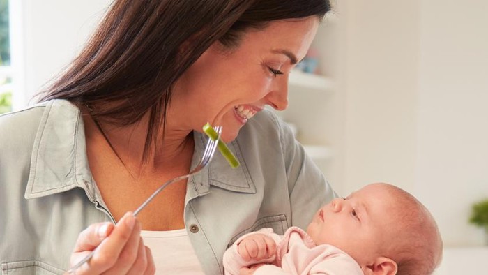 Young parents with baby girl having breakfast in bed