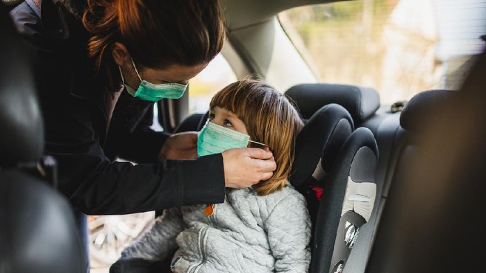 Shot of a toddler boy being secured in his car seat by his mother