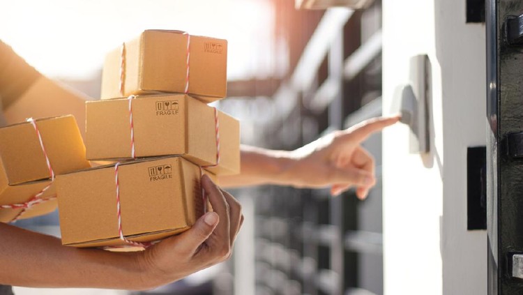Delivery man holding parcel boxes and ring the doorbell on the client's door in the morning background.