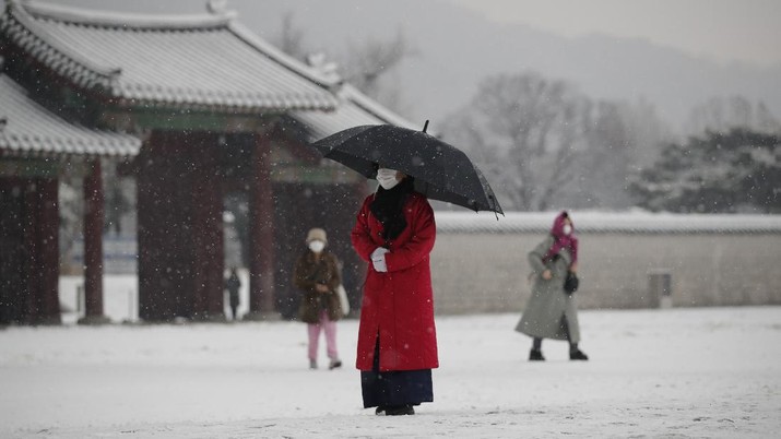 Korea Selatan An employee wearing a face mask as a precaution against the coronavirus uses an umbrella to take shelter from the snow at the Gyeongbok Palace, one of South Korea's well-known landmarks, in Seoul, South Korea, Sunday, Dec. 13, 2020. (AP Photo/Lee Jin-man)