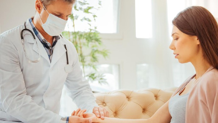 Do not worry. Male physician examining pulse of an expectant mother during an appointment at clinic.