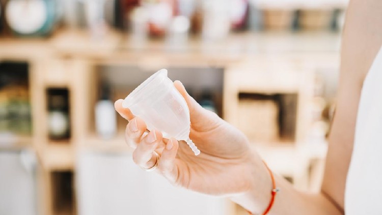 Girl holding in hands menstrual cup in sustainable plastic free store. Reusable female supplies for intimate hygiene. Woman buying modern alternative personal hygiene items in zero waste shop