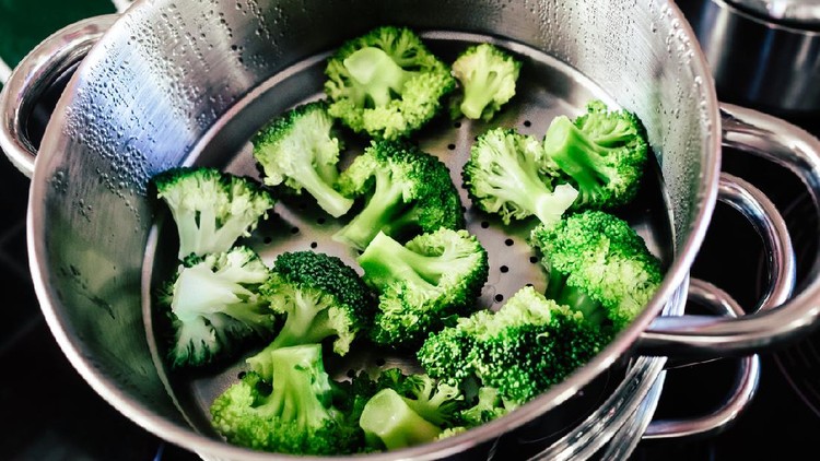 Broccoli florets being cooked in a steamer.