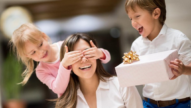 Happy kids surprising mom with a gift on mother's day