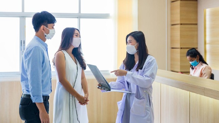 The doctor is talking to a couple to plan a family in the hospital.