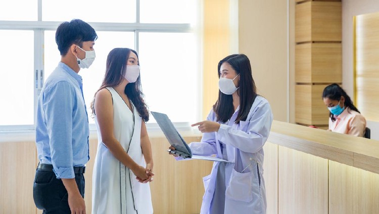The doctor is talking to a couple to plan a family in the hospital.