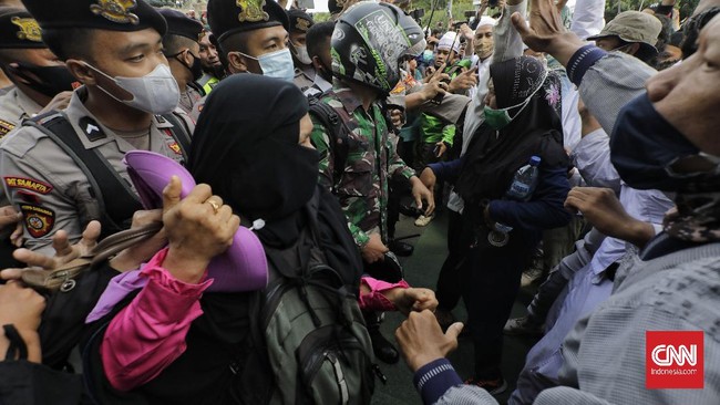 Sejumlah orang yang bagian dari massa Aksi 1812, termasuk kaum ibu, masih mencoba bertahan saat polisi berupaya membubarkan mereka.