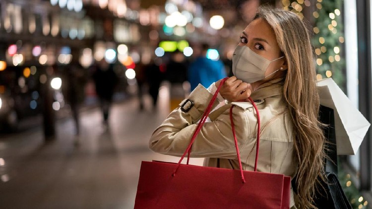 Happy woman Christmas shopping and wearing a facemask while carrying bags â COVID-19 pandemic concepts