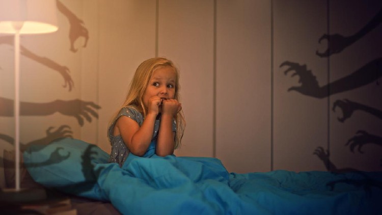 Nightmare for children. Little child girl is afraid of monsters in the dark of night.