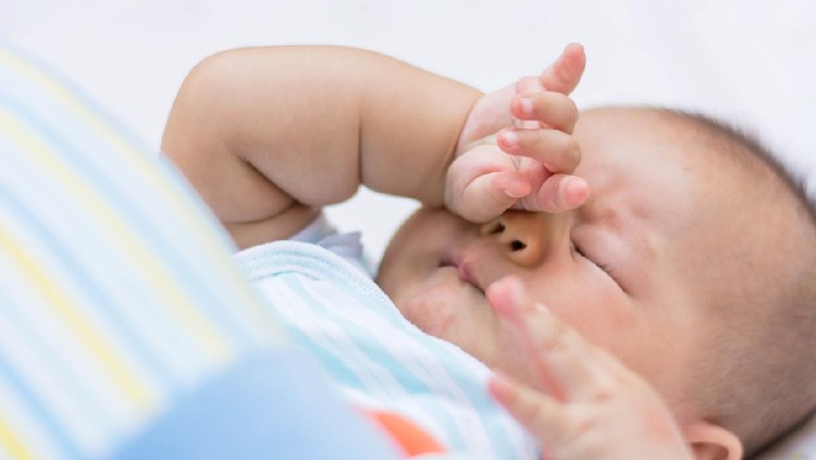 Baby rubbing it's eyes, feeling sleepy.