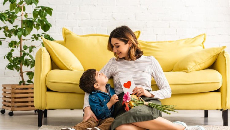 hari ibu Asian boy presenting his mother a red carnation flower for Mother's Day.