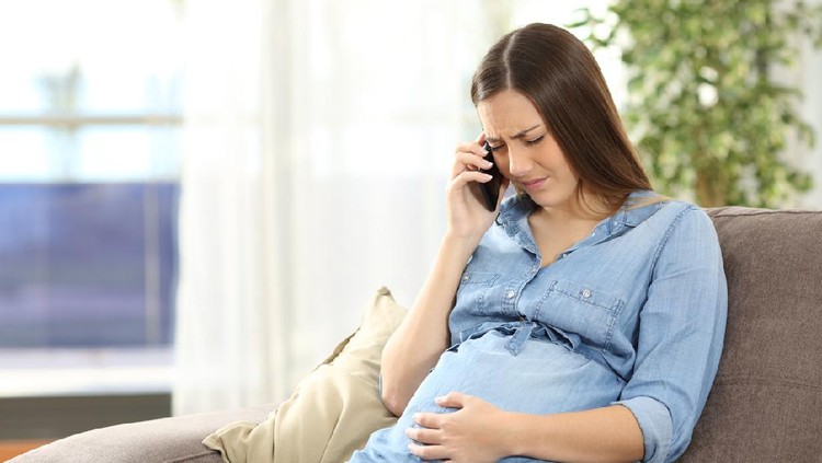 Side view of stressed woman getting regular contractions on bed
