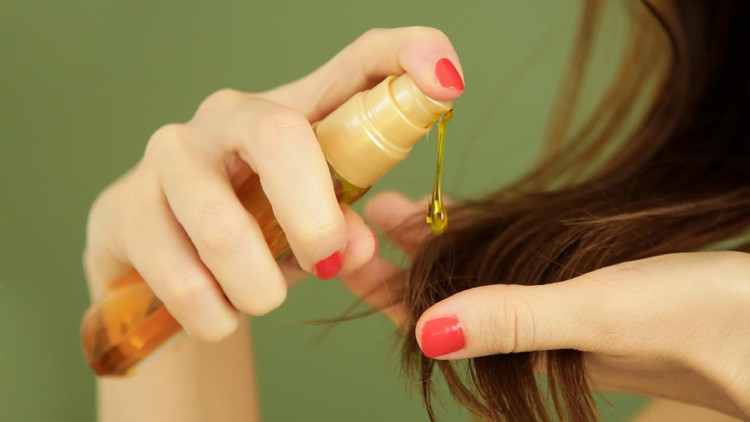 Woman applying oil on hair ends, split hair tips, dry hair or sun protection concept
