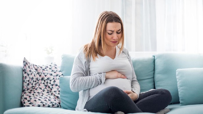 Young pregnant woman suffering from abdominal pain at home