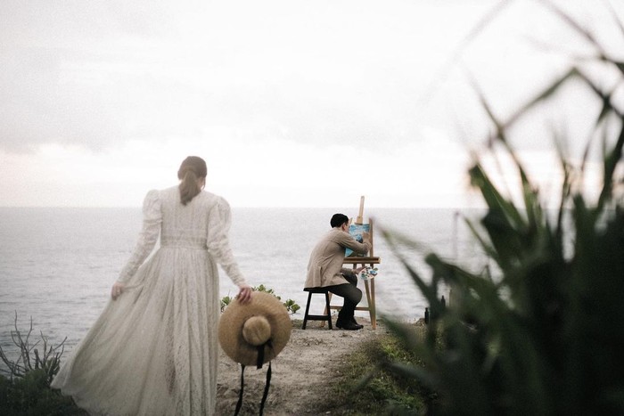 Pemotretan bertema outdoor selanjutnya mengambil latar di tepi pantai. Kali ini keduanya menggenakan busana bergaya vintage sembari berpose tengah melukis di kanvas. Sama-sama pecinta seni terutama lukisan, enggak heran kalau Billy dan Patricia memilih tema ini sebagai salah satu konsep foto prewedding mereka. (Foto: instagram.com/caliaphoto)