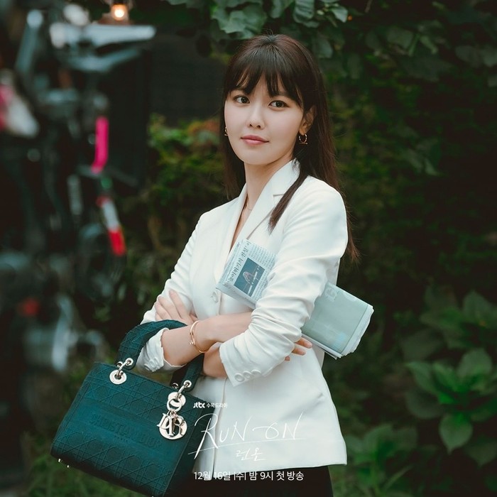Seo Dan Ah tak lepas dari blazer saat bekerja. Kali ini, dia tak mengunakan setelan satu warna. Ia memadukan tok span hitam dengan blazer putih. Dan Ah pun menambah tas kecil berwarna hijau dengan aksesoris gelang dan anting. (Foto:Instagram/jtbcdrama)