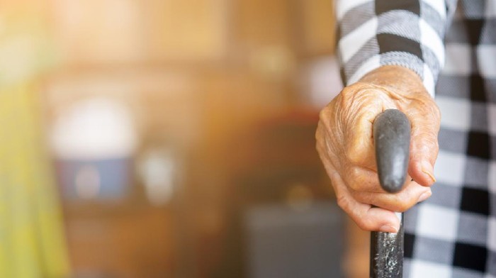 closeup senior woman hand holding walking cane to help stand at home , lifestyle of aging people concept