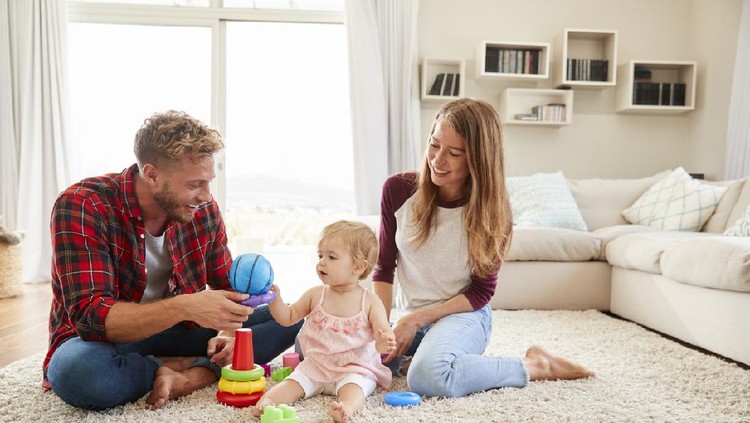 Young parents and toddler daughter playing in sitting room