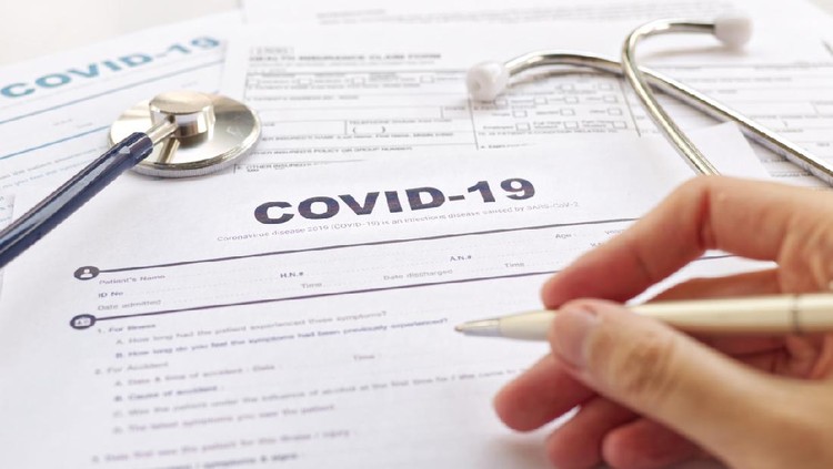 COVID-19 Health insurance concept. Blurring of hand holding pen and Stethoscope on health form. Focus on 