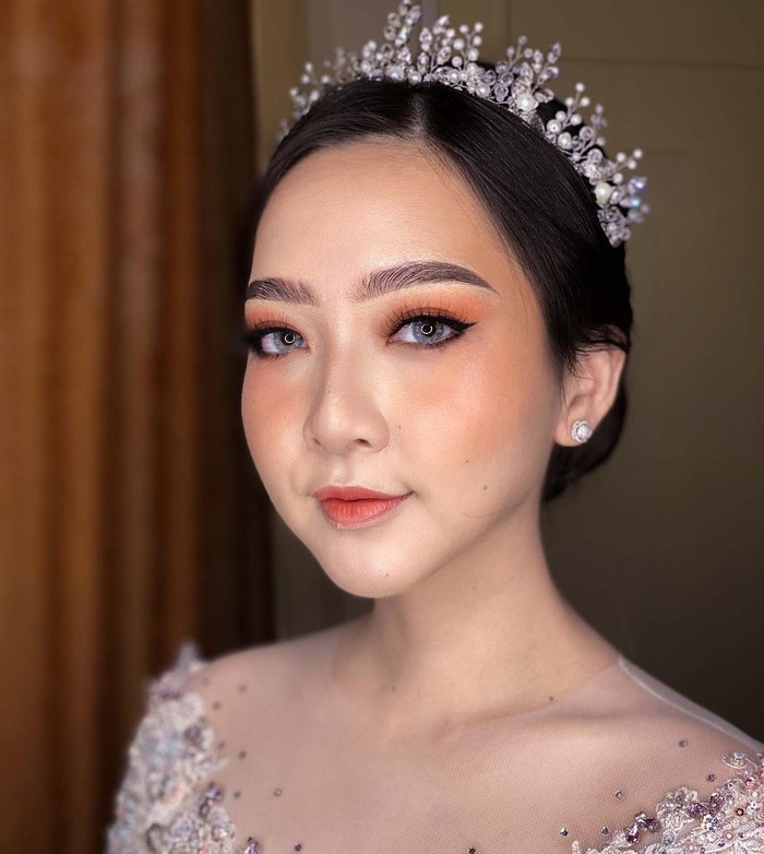 Beauty vlogger sekaligus dokter gigi yang satu ini resmi menikah dengan kekasihnya pada 26 Juli lalu. Ia tampil flawless dengan makeup bernuansa oranye. Konsep riasan natural yang dipadukan dengan eyeshadow, blush on, hingga lipstik serba oranye membuat tempilannya terlihat makin fresh ya. Kamu bisa tambahkan bulu mata dengan ketebalan ringan dan winked eyeliner untuk mempertegas riasan (Foto: www.instagram.com/astaririri/).
