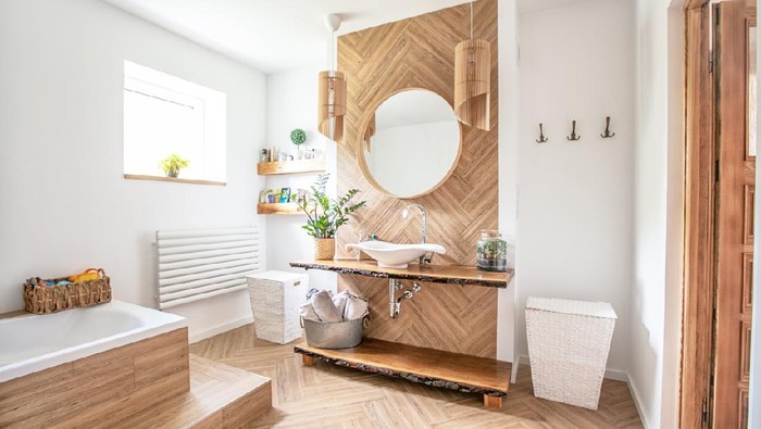 White sink on wood counter with a round mirror hanging above it. Bathroom interior.